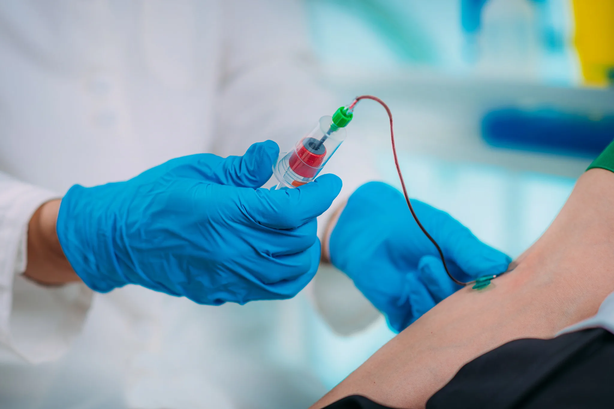 Medical worker with PPE taking blood sample from patient in a hospital